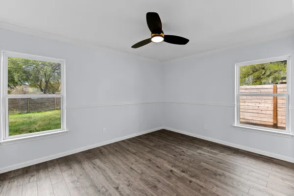 a view of an empty room with wooden floor and a window