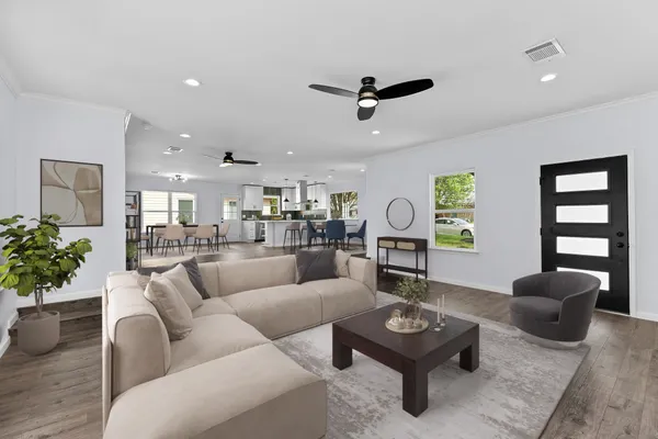 a living room with furniture a rug kitchen view and a window