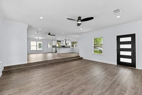 a view of an empty room with window and wooden floor