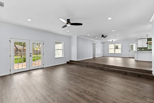 a view of an empty room with window and wooden floor