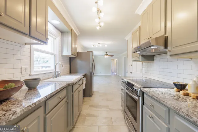 a kitchen with granite countertop a sink a counter top space and cabinets