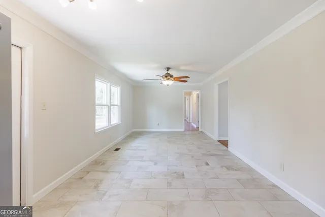 an empty room with windows and fan
