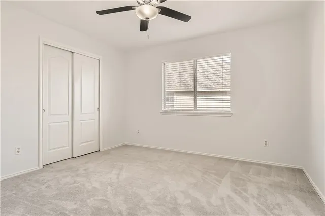 an empty room with a window and a ceiling fan