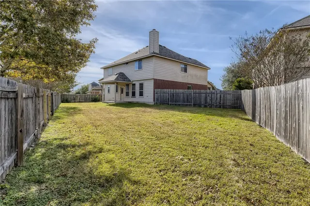 a view of a house with a yard and fence