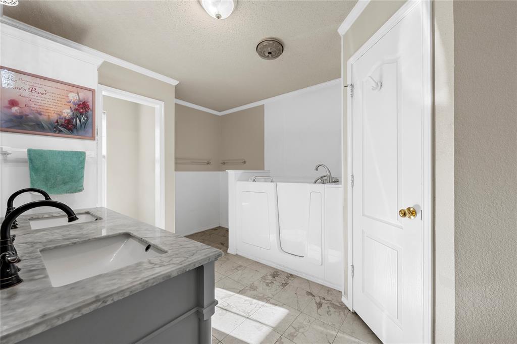 494 Westgate I Road Eddy, TX 76524 - Photo 14 of 34 Full bathroom with double vanity, ornamental molding, a textured ceiling, a garden tub, and light marble finish floors