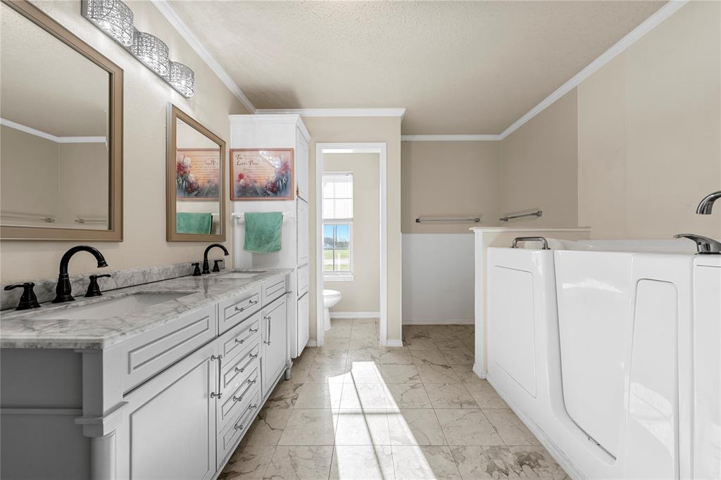 494 Westgate I Road Eddy, TX 76524 - Photo 15 of 34 Full bath with double vanity, ornamental molding, washer / clothes dryer, a garden tub, and light marble finish floors