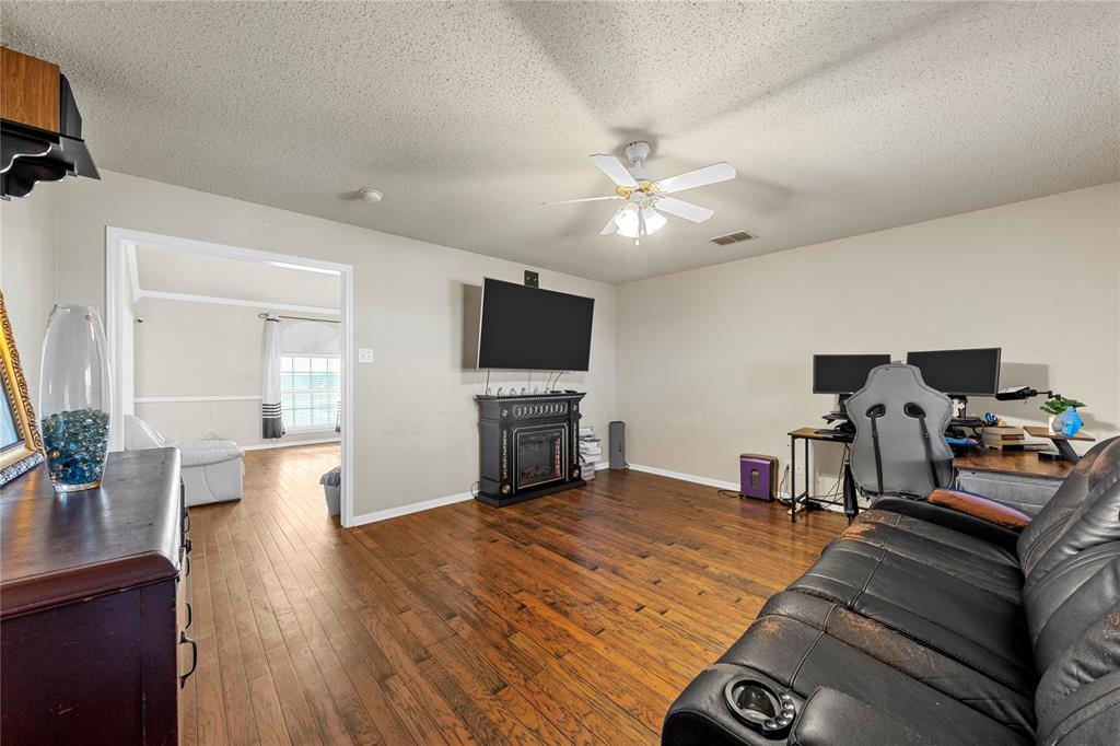 494 Westgate I Road Eddy, TX 76524 - Photo 21 of 34 Living room with dark wood-style flooring, a textured ceiling, a fireplace, and ceiling fan