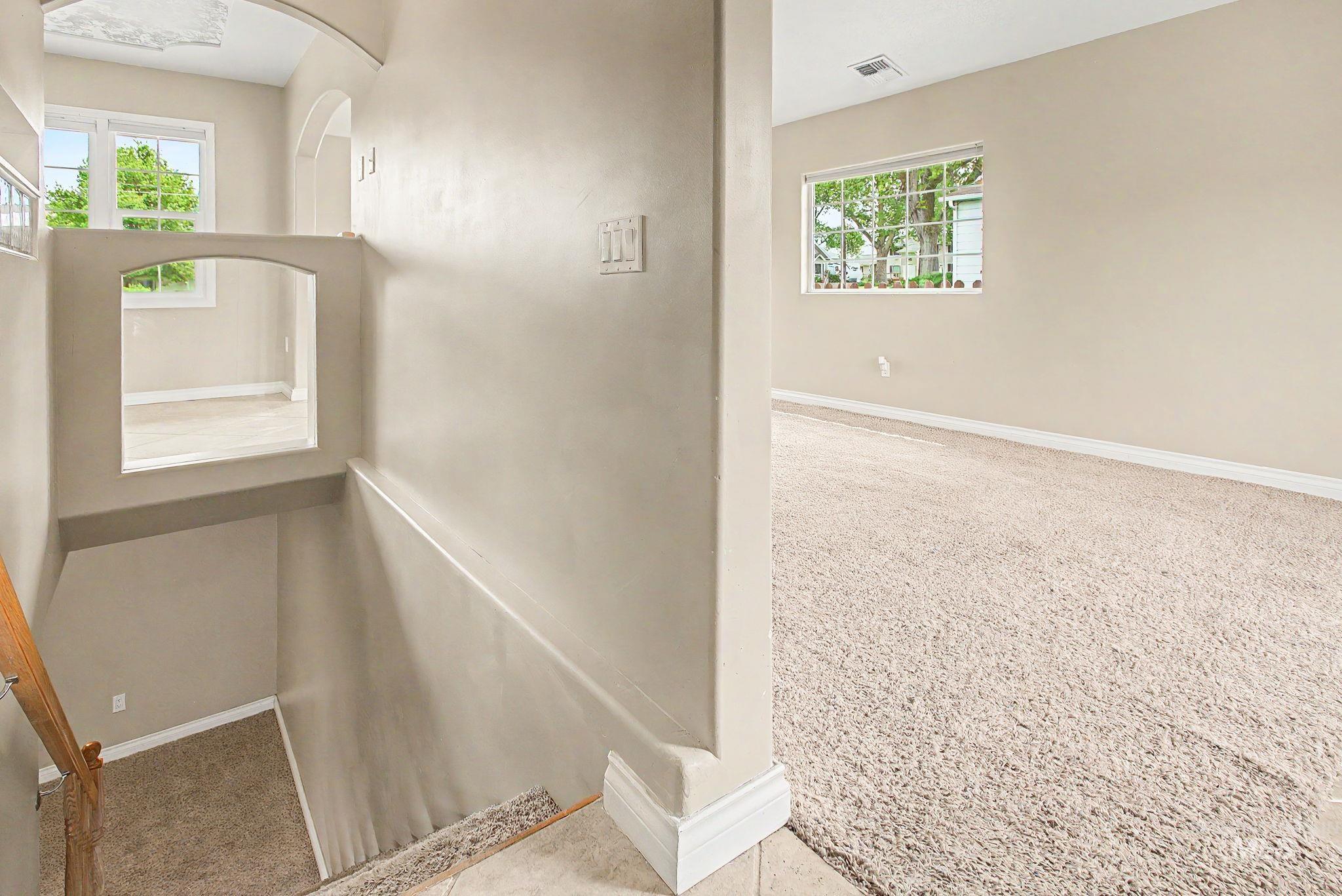 3314 6th Street Lewiston, ID 83501 - Photo 27 of 50 Carpeted interior featuring a half wall with an arched opening, neutral wall tones, white baseboards, and a window with natural light