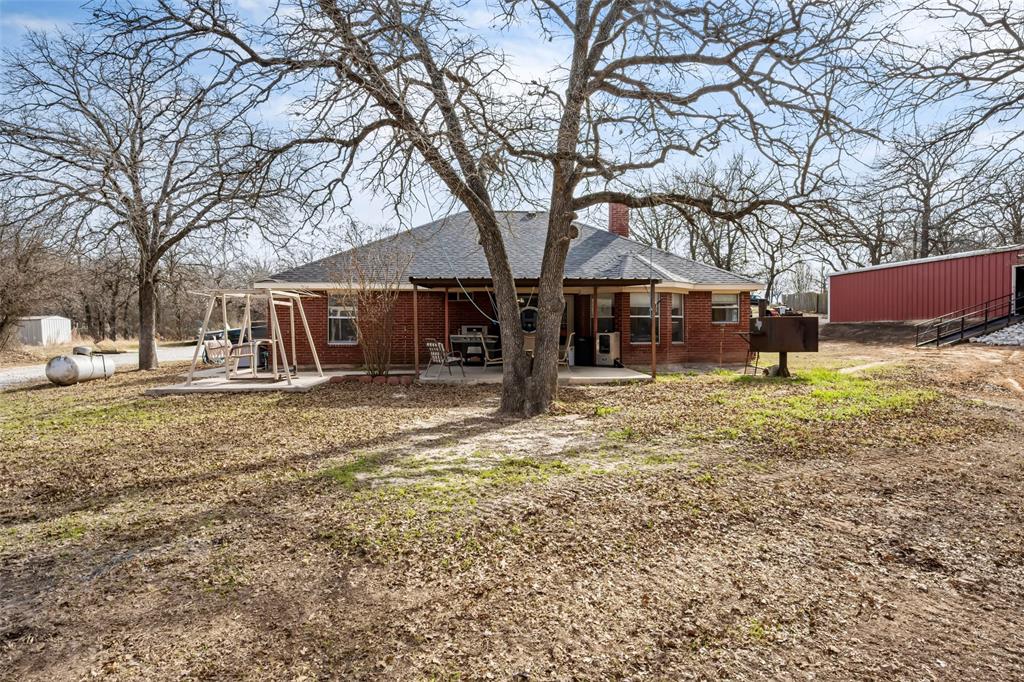 7698 Farm To Market 920 Poolville, TX 76487 - Photo 24 of 37 a backyard of a house with large trees and outdoor seating