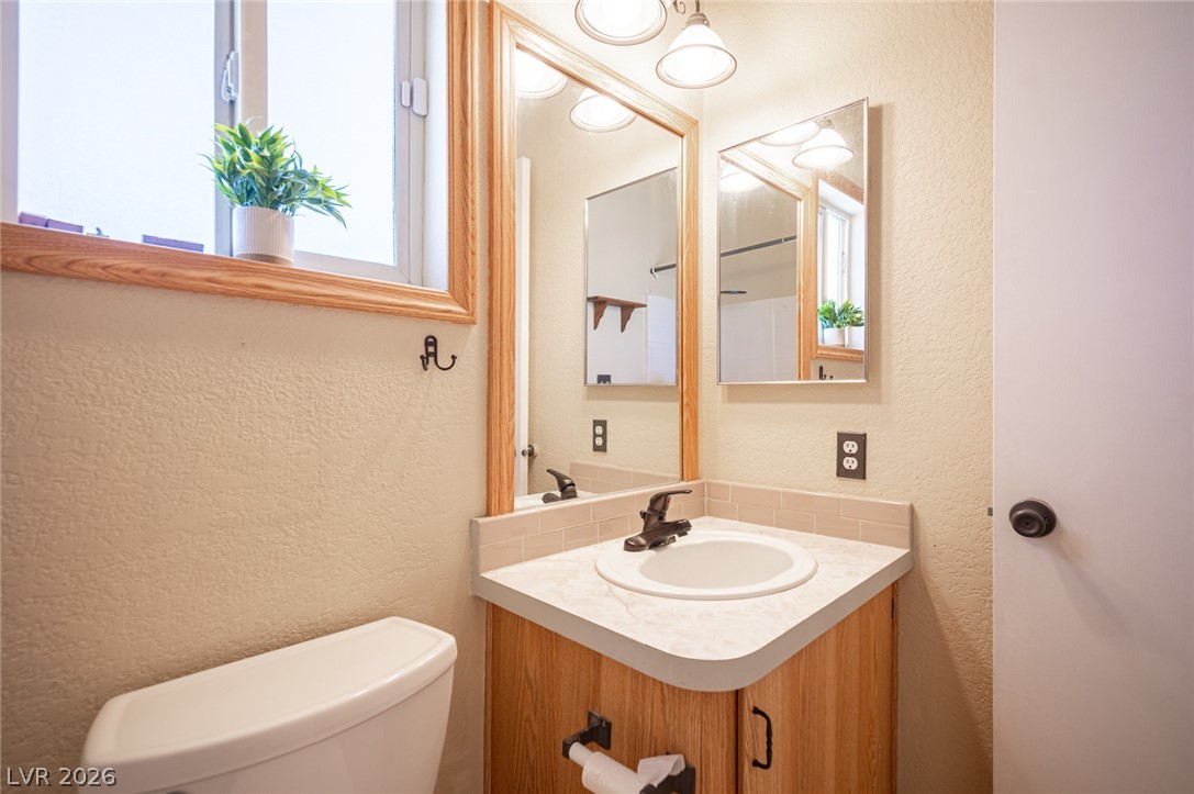 3200 Maple Road Pahrump, NV 89048 - Photo 30 of 53 A window-lit bathroom featuring a vanity with a circular sink and light wood cabinetry.