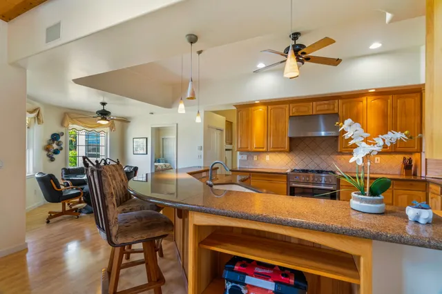 a kitchen with stainless steel appliances kitchen island granite countertop a table chairs in it and wooden floors