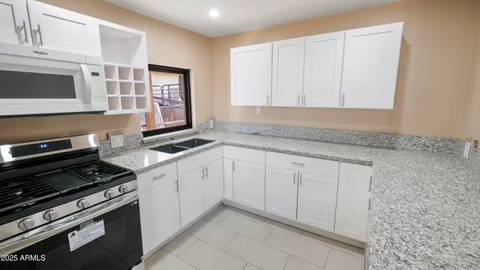 a kitchen with granite countertop white cabinets and stainless steel appliances