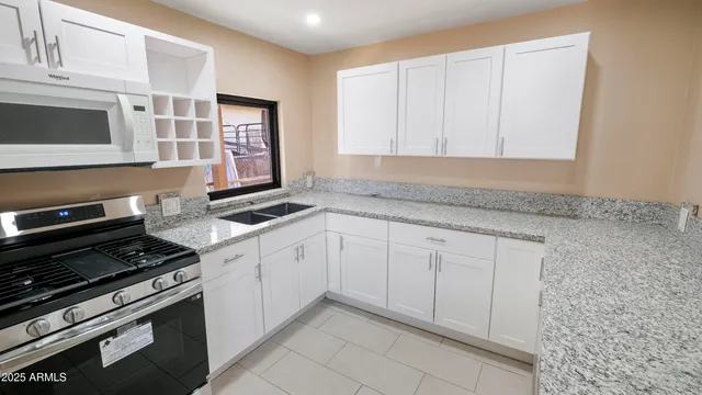 a kitchen with granite countertop white cabinets and stainless steel appliances