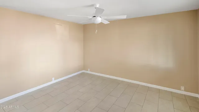 an empty room with a ceiling fan and carpet