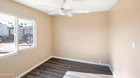 an empty room with wooden floor fan and windows