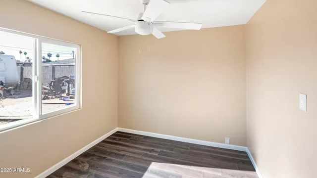 an empty room with wooden floor fan and windows
