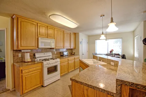 a large kitchen with stainless steel appliances granite countertop a stove a sink dishwasher and a refrigerator with wooden floor