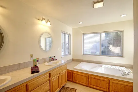 a bathroom with a granite countertop double vanity sink large mirror and a window