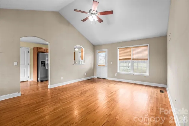 a view of an empty room with window and wooden floor