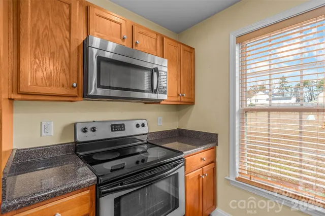 a kitchen with granite countertop a sink a stove and cabinets