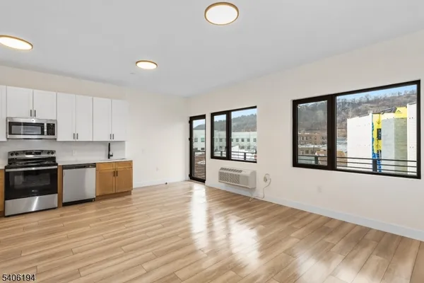 a large kitchen with stainless steel appliances granite countertop a stove a sink and a large window