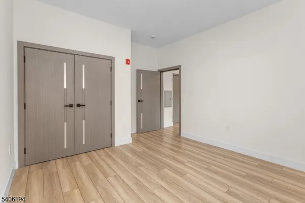 a view of a hallway with wooden floor and closet area