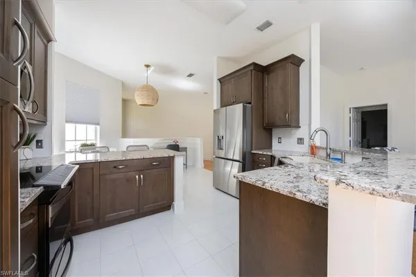 a kitchen with stainless steel appliances granite countertop a sink refrigerator and cabinets