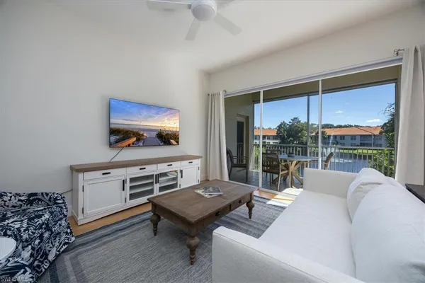 a living room with furniture a flat screen tv and a floor to ceiling window
