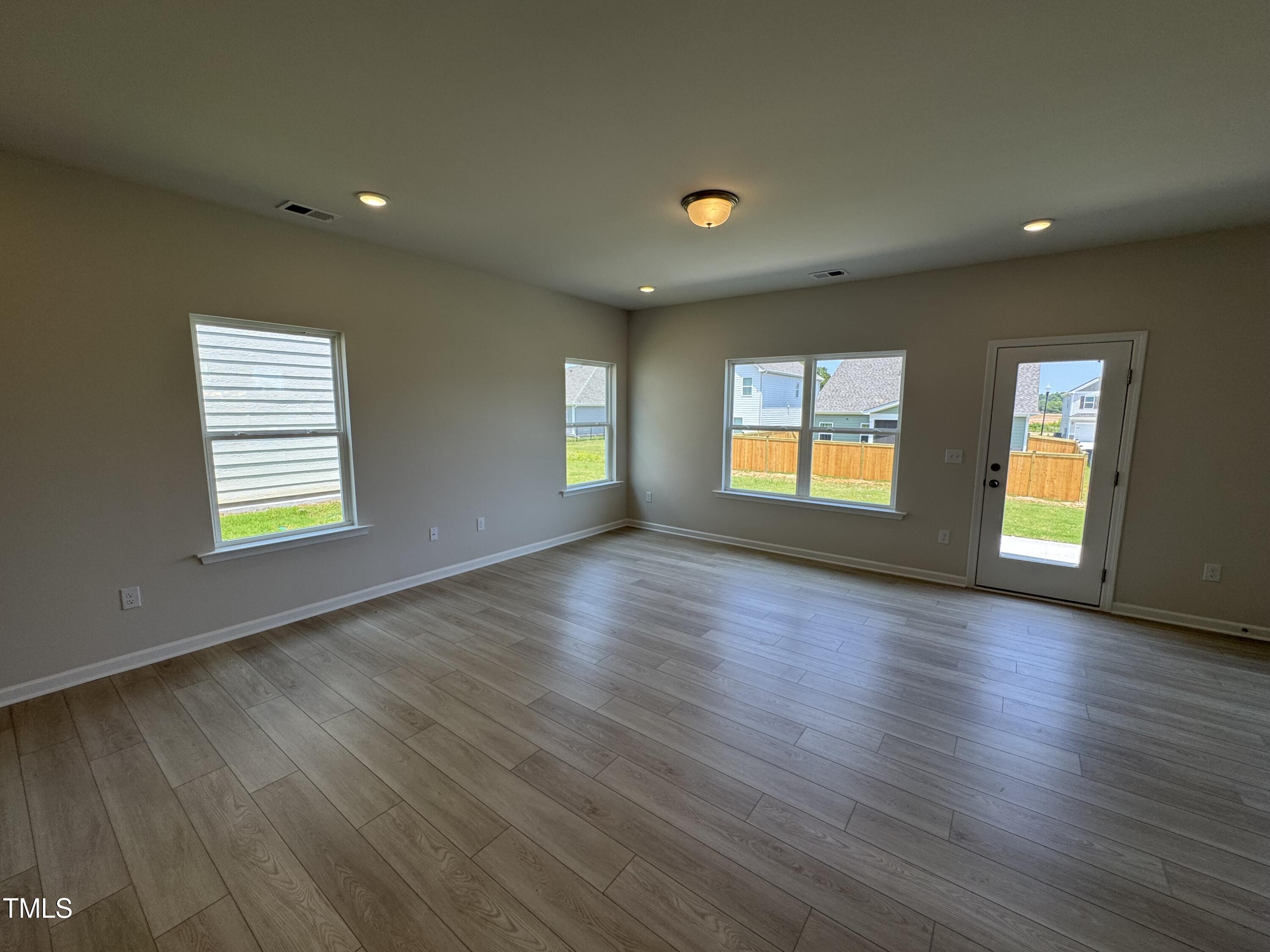 76 Commons Circle Clayton, NC 27520 - Photo 4 of 29 an empty room with wooden floor and windows