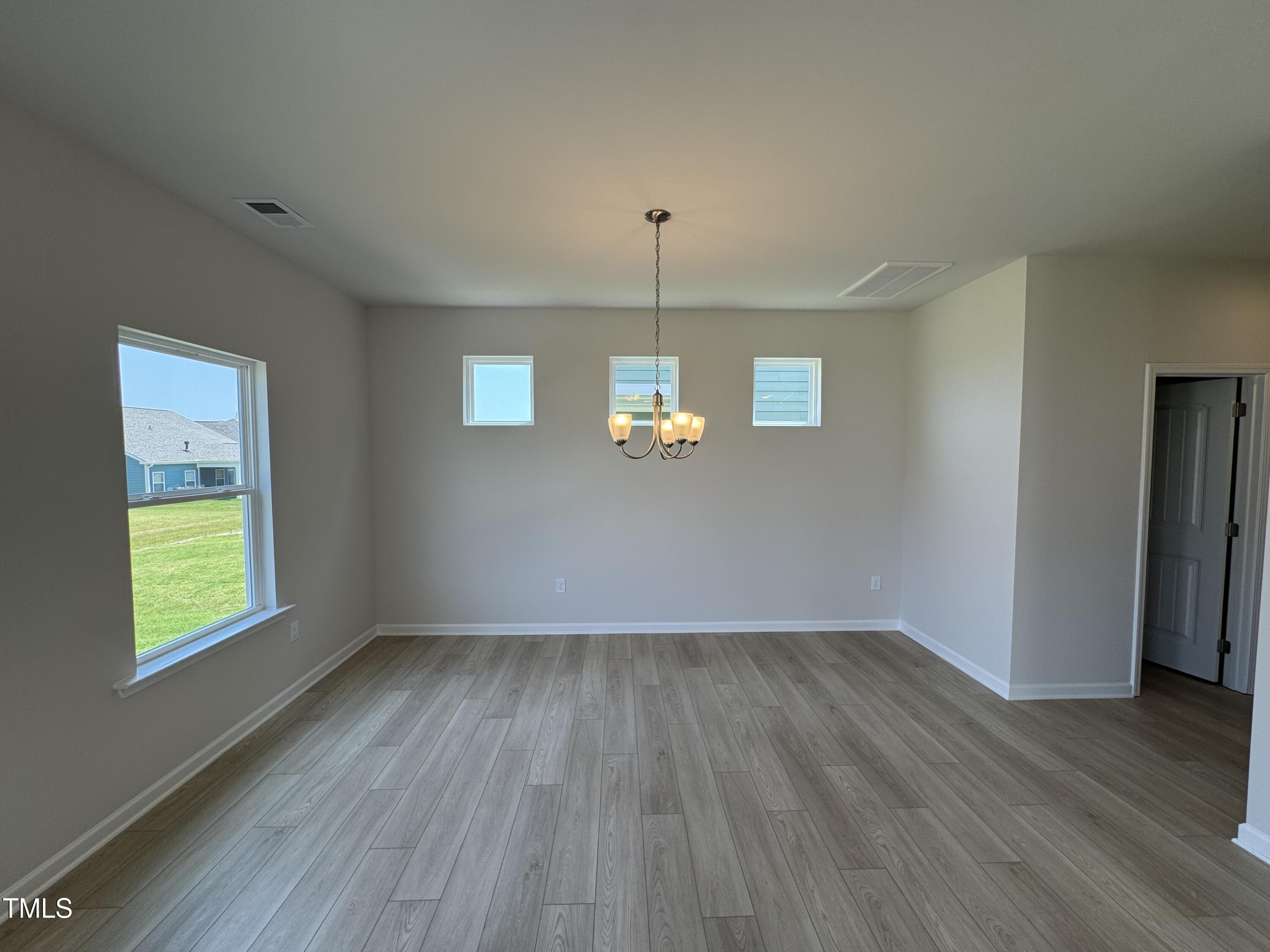 76 Commons Circle Clayton, NC 27520 - Photo 5 of 29 an empty room with wooden floor and windows