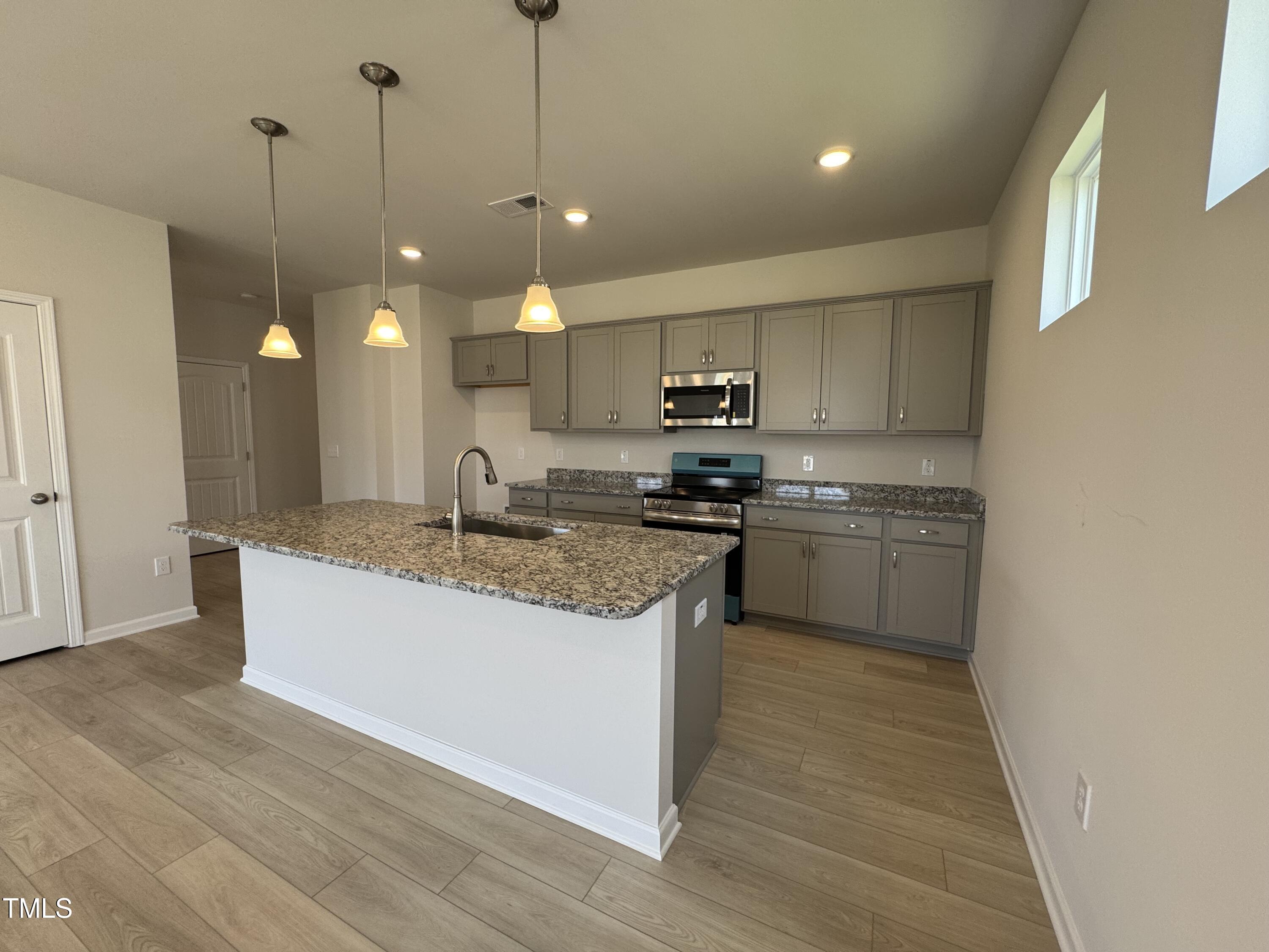 76 Commons Circle Clayton, NC 27520 - Photo 7 of 29 a kitchen with kitchen island a sink stainless steel appliances and cabinets