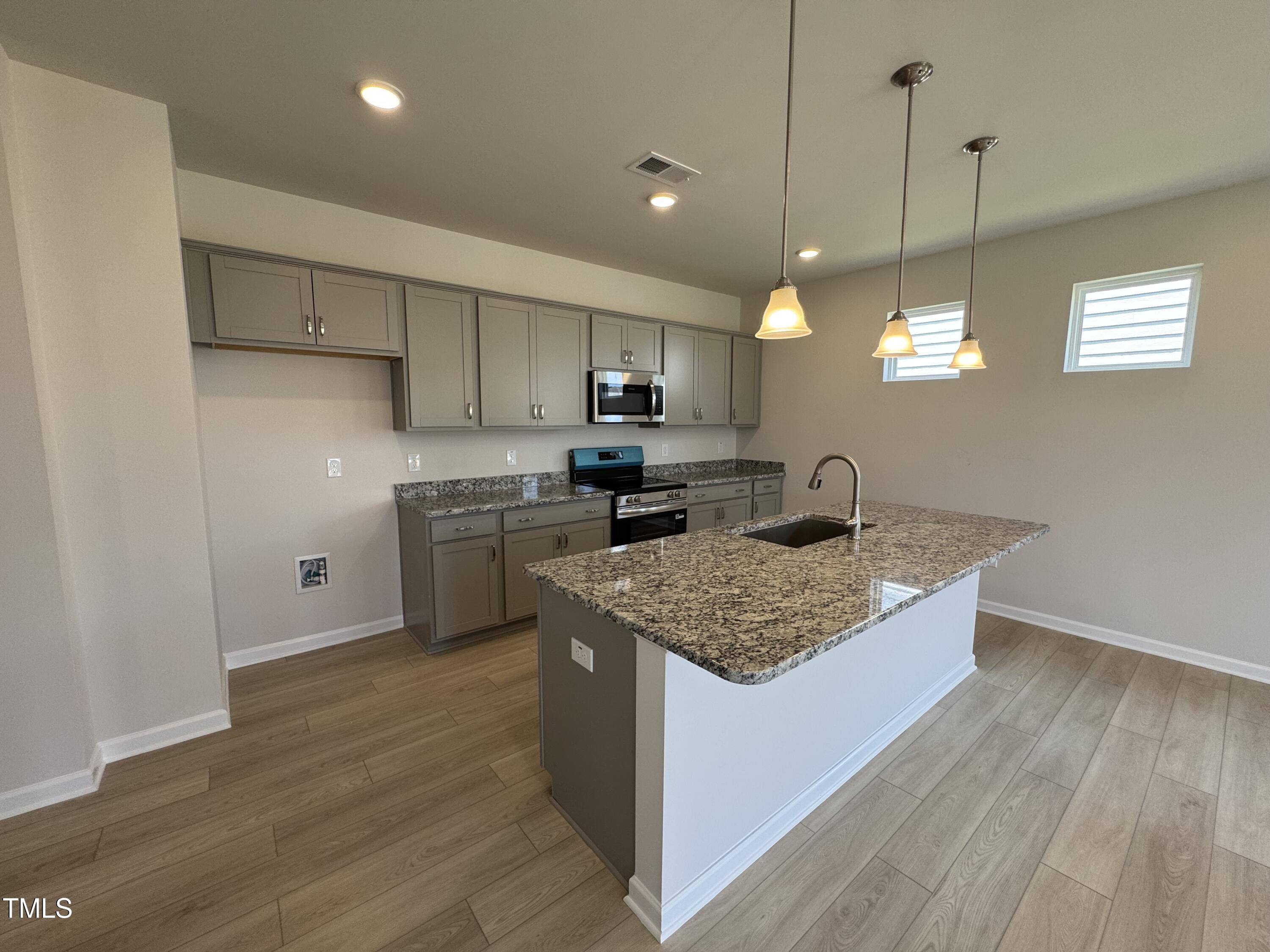 76 Commons Circle Clayton, NC 27520 - Photo 8 of 29 a kitchen with stainless steel appliances granite countertop a sink a stove and a wooden floors