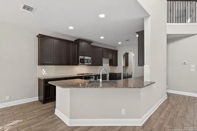 a large kitchen with kitchen island a large counter top and wooden floors