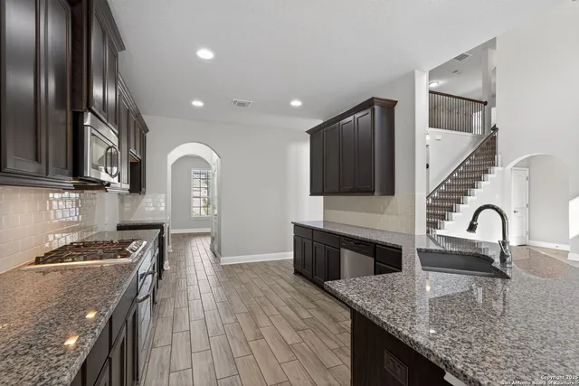 a kitchen with stainless steel appliances granite countertop a sink a stove and a refrigerator