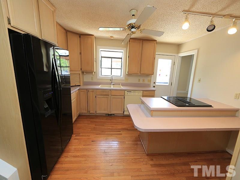 1504 Stratlen Court Raleigh, NC 27615 - Photo 4 of 17 a room with kitchen island a sink wooden floor and stainless steel appliances