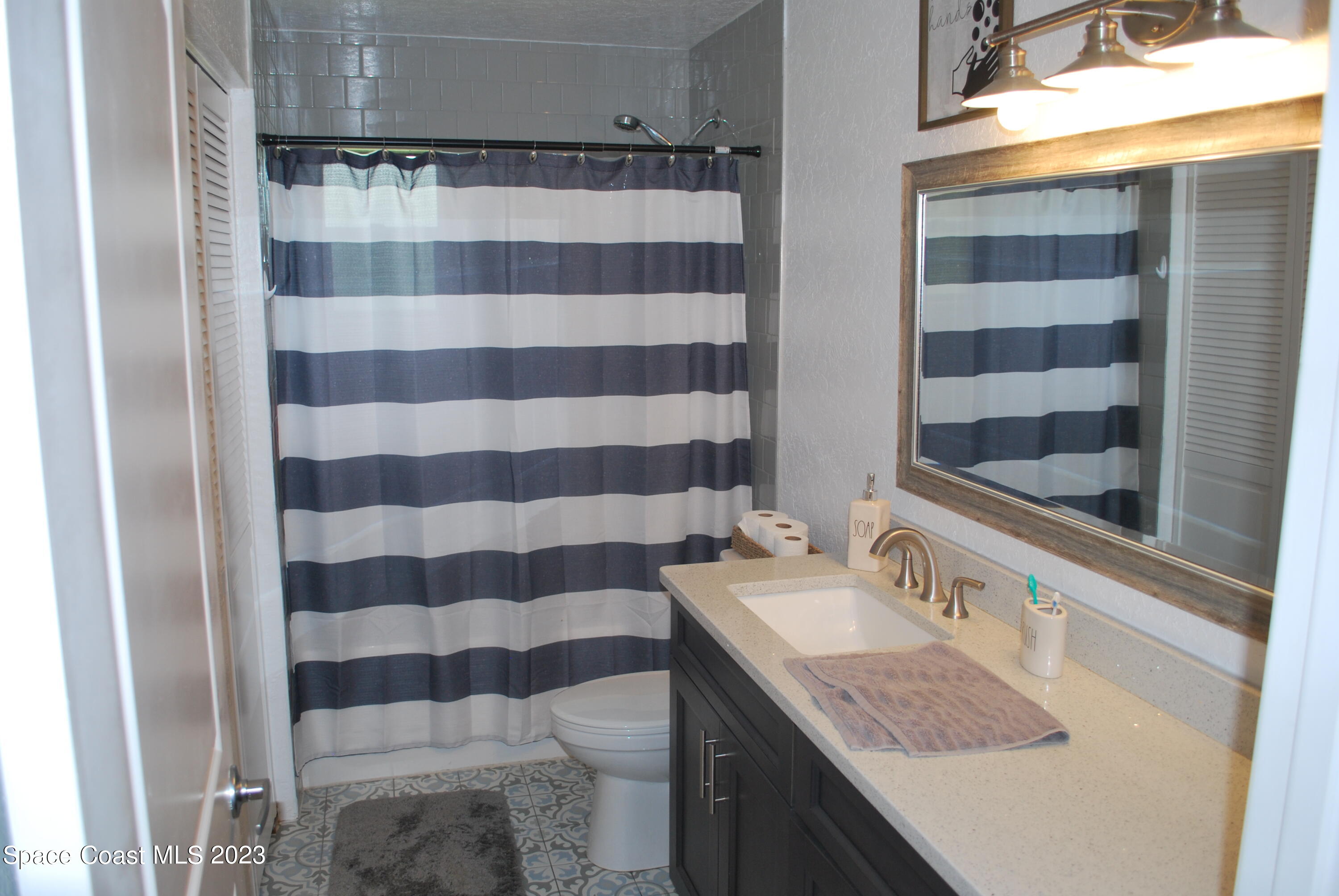 2745 Corey Road Malabar, FL 32950 - Photo 9 of 39 a bathroom with a granite countertop sink a toilet and shower