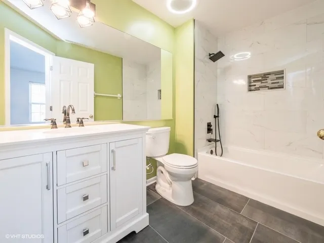 a bathroom with a double vanity sink a toilet a mirror and shower