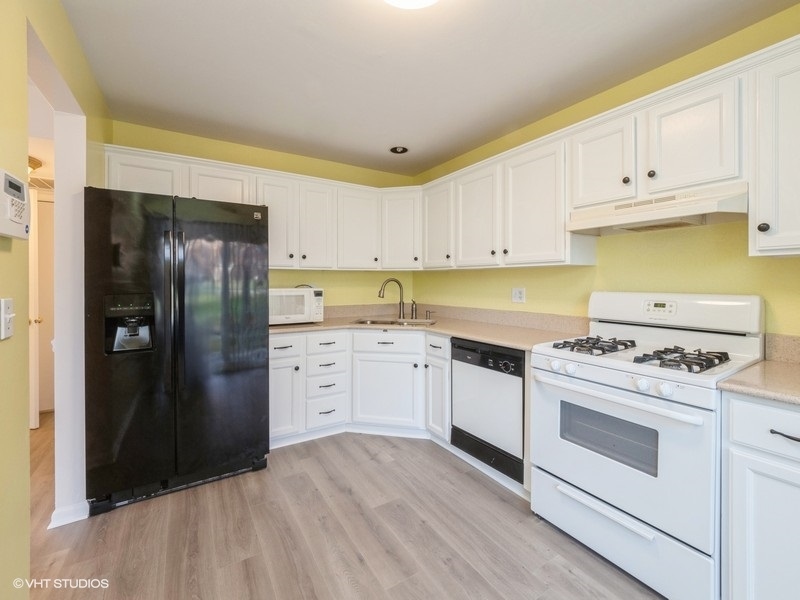 140 Crescent Lane Schaumburg, IL 60193 - Photo 7 of 21 a kitchen with white cabinets and stainless steel appliances