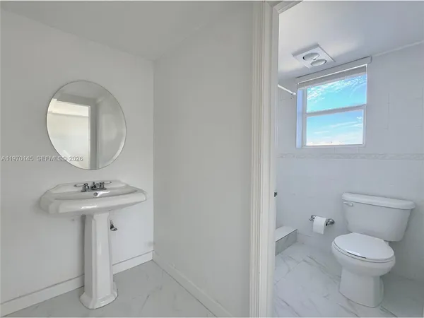 a bathroom with a toilet a sink and mirror