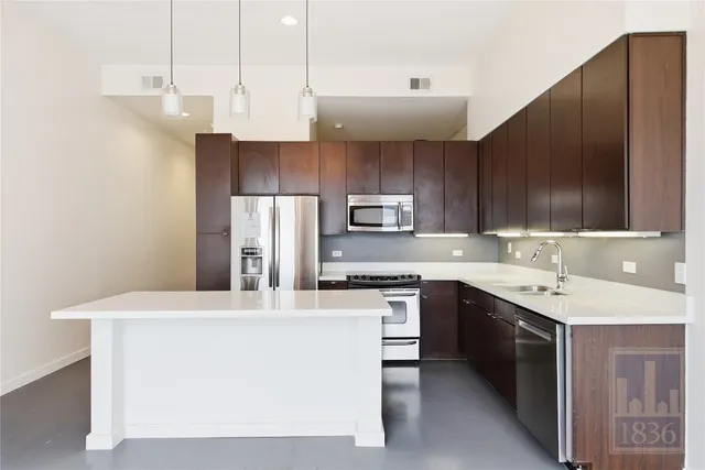 a kitchen with stainless steel appliances a sink a stove a refrigerator and cabinets