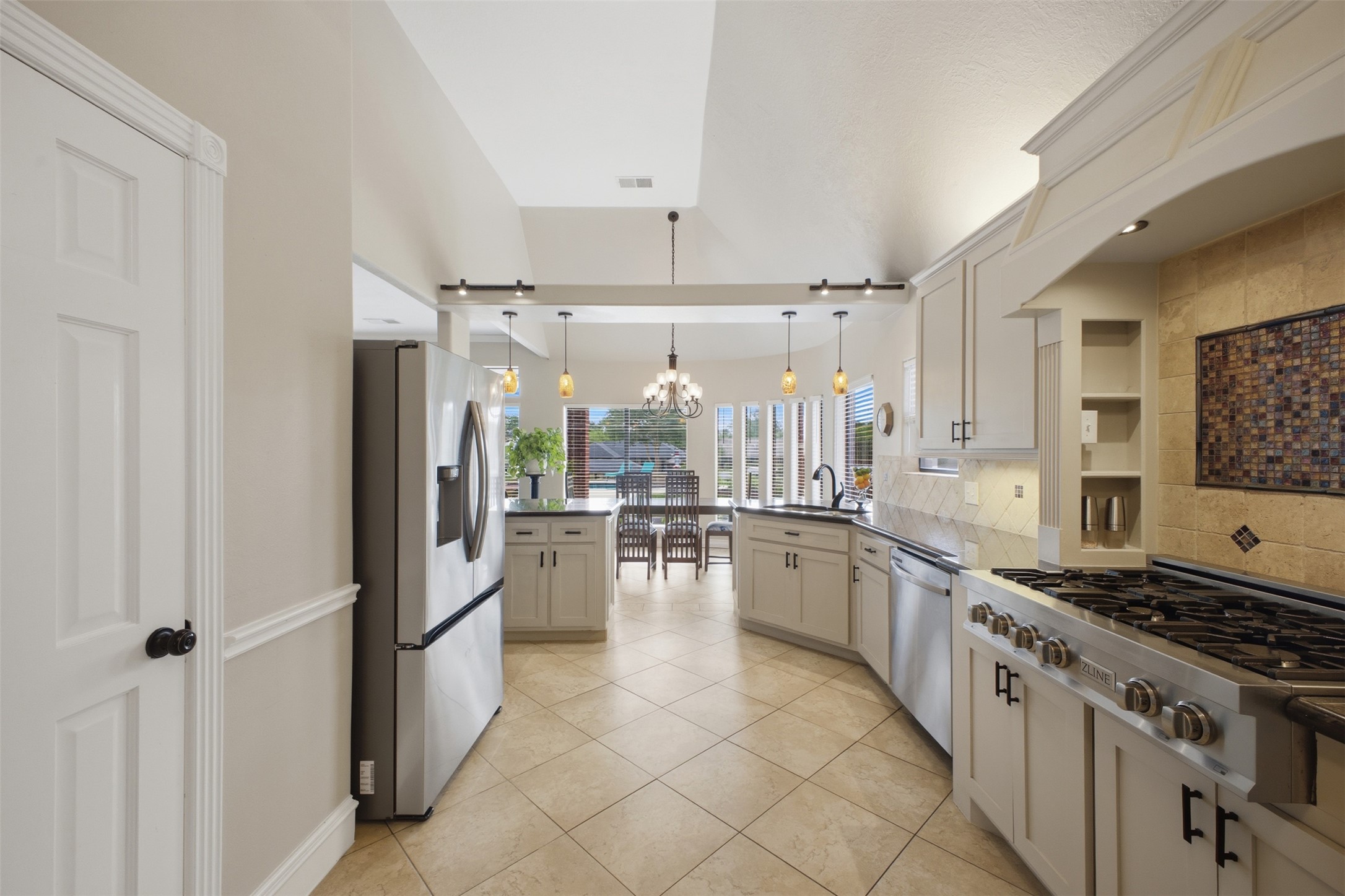12710 Aries Loop Willis, TX 77318 - Photo 13 of 40 The kitchen features light-colored cabinetry, stainless steel appliances, and a tiled backsplash with an accent mosaic