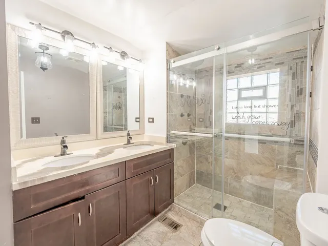 a bathroom with a double vanity sink toilet mirror and shower
