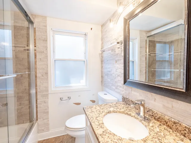 a bathroom with a granite countertop sink toilet and shower