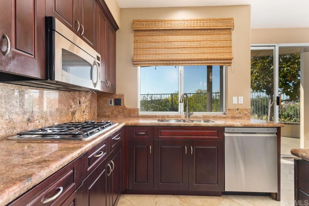 6947 Dusty Rose Place Carlsbad, CA 92011 - Photo 11 of 50 a kitchen with stainless steel appliances granite countertop a sink and a stove