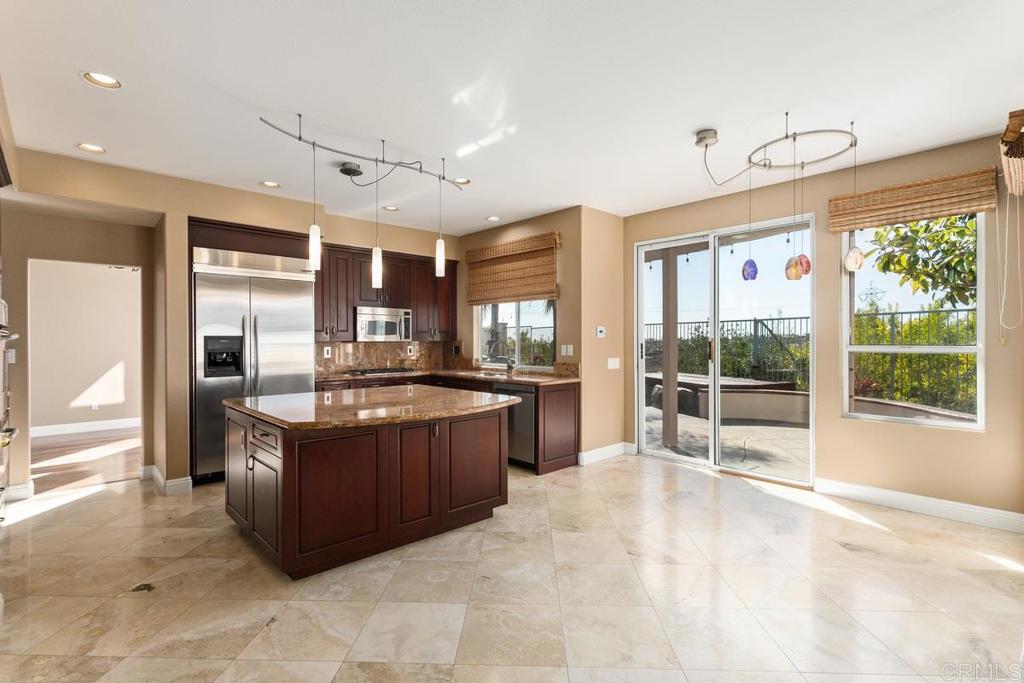 6947 Dusty Rose Place Carlsbad, CA 92011 - Photo 13 of 50 a large kitchen with kitchen island granite countertop a large window and stainless steel appliances