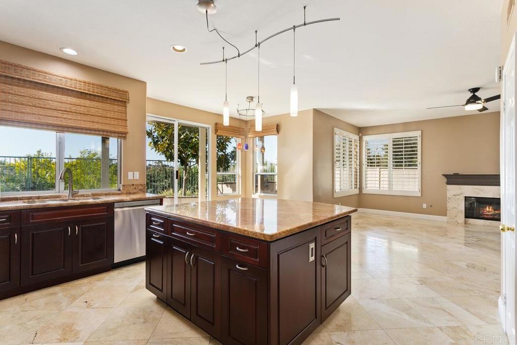 6947 Dusty Rose Place Carlsbad, CA 92011 - Photo 14 of 50 a kitchen with kitchen island granite countertop a stove a sink and dishwasher wooden cabinets with granite countertops