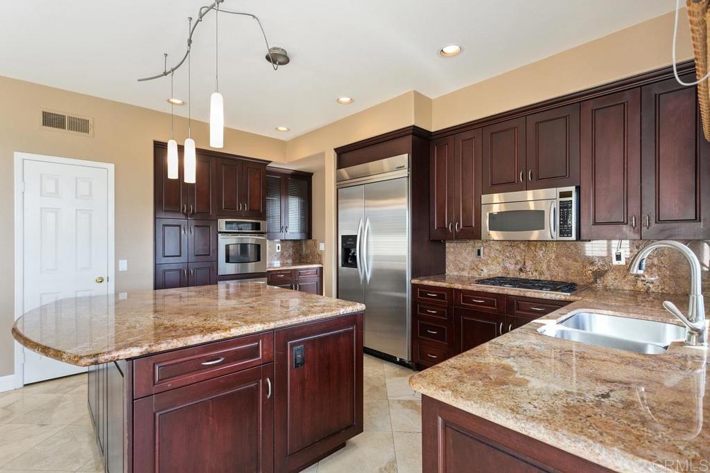 6947 Dusty Rose Place Carlsbad, CA 92011 - Photo 16 of 50 a kitchen with stainless steel appliances granite countertop a sink a stove and a refrigerator