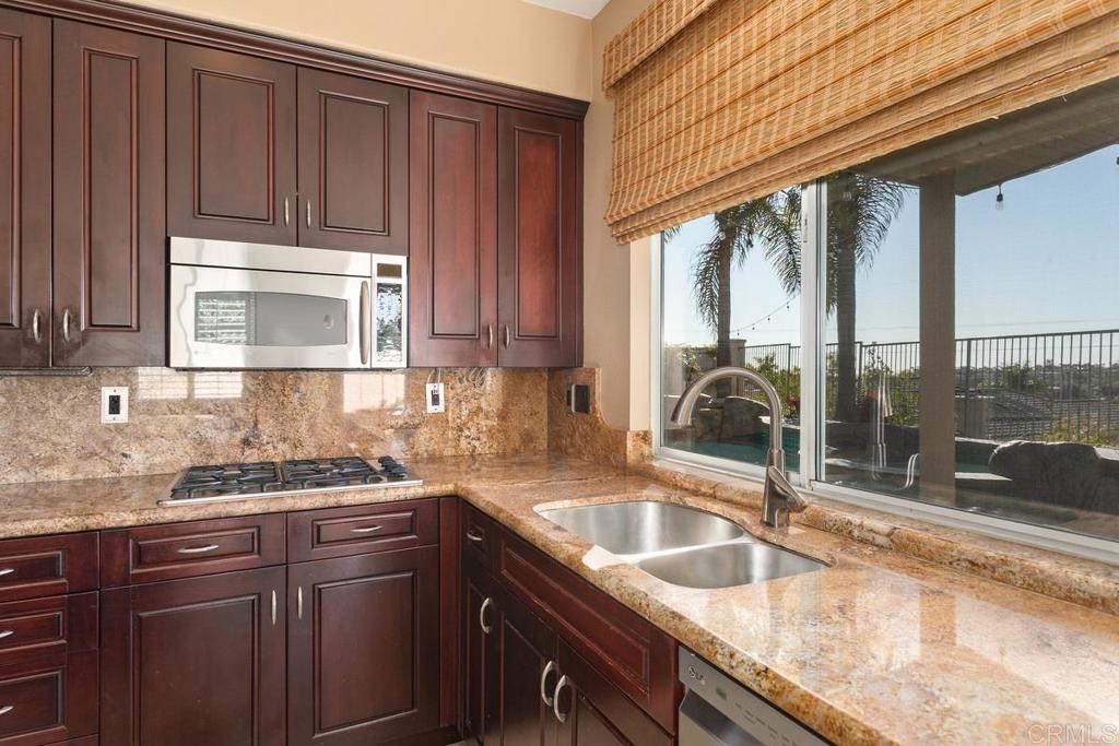 6947 Dusty Rose Place Carlsbad, CA 92011 - Photo 17 of 50 a kitchen with granite countertop a sink stove and cabinets