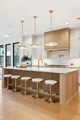 a kitchen with stainless steel appliances kitchen island a table chairs in it and wooden floors