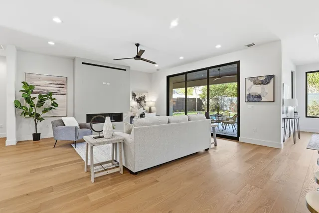 a living room with furniture large window and wooden floor